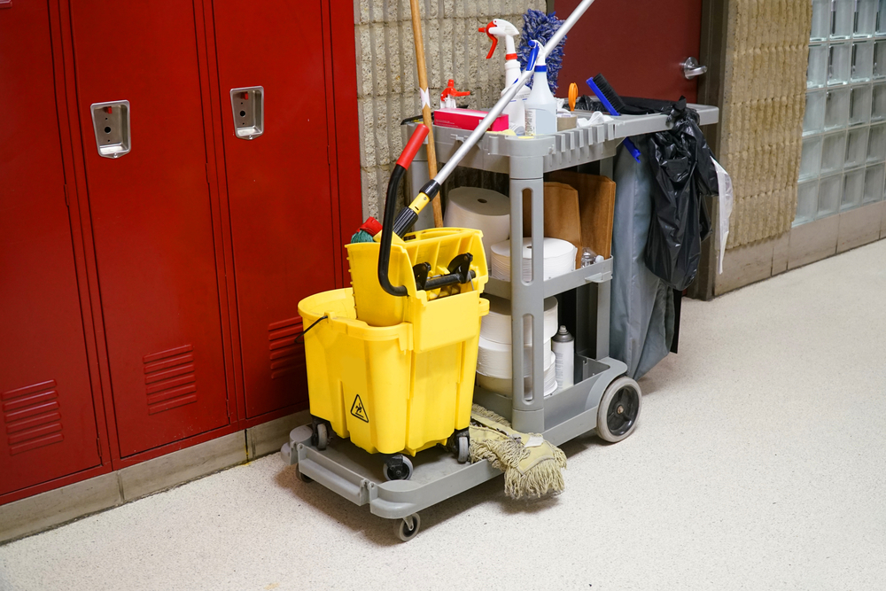 A cleaning cart with supplies sitting by commercial lockers.